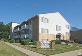This 400 square foot apartment in Topeka, Kansas, offers a thoughtfully designed living space on a single floor. The heart of the home is an open-concept living area, illuminated by natural light from large windows and vertical blinds. The hardwood flooring throughout adds warmth and character to the space.

The efficient kitchen is equipped with white cabinetry, providing ample storage. It features essential appliances including a refrigerator and electric stove. The countertops appear to be a dark, contrasting material, possibly granite or laminate.

Adjacent to the main living area is a surprisingly spacious closet, offering generous storage solutions. The closet includes a built-in clothes rail and appears to have additional space for shelving or organizational units.

The apartment also includes a bathroom, glimpsed in one image, which seems to feature a shower/tub combination. The overall design of the space emphasizes functionality and maximizes the use of the available square footage, creating a cozy yet practical living environment.