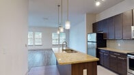 Located at 5290 Big Island Dr in Jacksonville, FL, this well-appointed 2-bedroom, 2-bathroom residence offers a thoughtfully designed single-floor layout. The open-concept kitchen and living area serves as the heart of the home, featuring a large granite-topped island with a built-in sink and elegant pendant lighting. Dark espresso cabinetry, a mosaic tile backsplash, and a full suite of stainless steel appliances — including a refrigerator, range, microwave, and dishwasher — complete the kitchen. Light tile flooring transitions seamlessly into wood-style plank flooring that extends throughout the living and bedroom areas. The spacious living room is bathed in natural light from a generous bank of windows and is finished with a ceiling fan overhead. The primary bedroom is generously sized, offering dedicated closet space and its own en-suite bathroom equipped with a granite vanity, a glass-enclosed walk-in shower, a soaking tub, and tile flooring. The second bedroom also features wood-style flooring, a ceiling fan, and ample natural light. The second bathroom includes a pedestal sink and clean, neutral finishes. Both bedrooms include closets, completing this functional and modern floor plan.