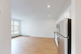 Located at 223 Garden St in South Burlington, Vermont, this one-bedroom, one-bathroom residence offers a clean, modern design with a highly functional single-floor layout. Light hardwood flooring runs throughout the space, complementing the bright white walls and recessed lighting that create a consistently airy atmosphere.

The open-concept main area seamlessly combines the living room, dining area, and kitchen into one cohesive space. The kitchen is well-appointed with white shaker-style cabinetry extending to the ceiling for ample storage, a full suite of stainless steel appliances including a refrigerator, electric range, over-the-range microwave, and dishwasher, plus a stainless steel sink with a modern faucet and neutral-toned countertops. Baseboard heating runs along the perimeter walls throughout the unit.

The bedroom is a comfortable, well-proportioned room featuring a large multi-pane window that brings in generous natural light and views of the surrounding neighborhood, along with a wall-mounted air conditioning unit and recessed lighting. Two closets provide practical storage solutions.

The bathroom maintains the home's clean aesthetic with white cabinetry, a wide vanity with a large mirror, and a tub/shower combination fitted with grab bars. The unit's consistent use of light tones and modern materials gives it a fresh, move-in-ready appeal.
