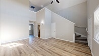 Located at 6419 Skyline Dr in Houston, TX, this two-story, 2-bedroom, 2-bathroom home offers a thoughtfully designed layout spread across two floors. The main floor is the larger of the two and features an open living and dining area anchored by striking soaring ceilings that create an airy, expansive feel. A ceiling fan adds comfort to the living space, while light wood-look flooring flows consistently throughout, lending warmth and cohesion to the home. The kitchen is well-appointed with white shaker cabinets, granite countertops, a tile backsplash, stainless steel appliances, and ample storage. Neutral gray tones on the walls throughout provide a clean, modern backdrop. The upper floor houses the spacious primary bedroom, which features vaulted ceilings and a large window that brings in generous natural light. It is complemented by a walk-in closet with full shelving and rod systems. The secondary bedroom also enjoys natural light through large windows. A second walk-in closet provides additional storage. Both bathrooms are finished with wood-look flooring, and the upper bathroom features a marble-tiled shower enclosure and a sloped ceiling that adds architectural character. Three closets total ensure plentiful storage throughout the home.