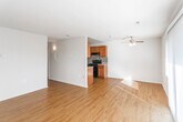 This single-floor residence offers a thoughtfully laid-out interior that balances functionality and comfort throughout. The open-concept living and dining area is bright and welcoming, featuring warm hardwood-style flooring that extends throughout the main living spaces. Natural light streams in through large sliding glass doors fitted with vertical blinds, while a ceiling fan overhead adds to the airy feel of the room.

The galley-style kitchen is efficiently designed with rich medium-toned wood cabinetry lining both sides, complemented by granite-look countertops and a striking mosaic tile backsplash in neutral tones. Black appliances, including a gas range, refrigerator, and built-in range hood, provide a cohesive, modern look. The kitchen connects seamlessly to the living area through a partial wall opening.

The bedrooms are carpeted for comfort and benefit from natural light through wide windows with blinds. One bedroom includes a built-in closet with shelving, while another features access to an adjoining hallway. The bathroom is clean and practical, offering a full tub and shower combination with chrome fixtures, a toilet, and hardwood-style flooring that ties the space together neatly.