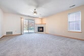 Located at 8550 Greenway Blvd in Middleton, WI, this single-floor, 2-bedroom, 2-bathroom home offers a well-organized and functional layout. The open-concept living and dining area is anchored by a corner gas fireplace with a wood-trimmed surround, plush carpet, a ceiling fan, and a sliding glass door that fills the space with natural light and provides outdoor access. The kitchen features white cabinetry, a white countertop peninsula with a built-in sink and breakfast bar overhang, and recessed lighting — all flowing seamlessly into the main living area through an elegant arched passage with decorative columns. The generously sized primary bedroom includes a ceiling fan, a large window, and access to a walk-in closet outfitted with built-in shelving and hanging rods. The second bedroom is equally well-proportioned, also featuring a ceiling fan and natural light. Both bathrooms are finished with white vanities, white countertops, tile flooring, and well-lit mirrors. A dedicated in-unit laundry room houses a full-size washer and dryer. With four closets and a central hallway, storage and circulation throughout the home are practical and efficient.
