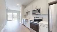Located at 1126 Shady Ln in Austin, TX, this efficiently designed single-floor unit offers a thoughtfully arranged layout that maximizes every square foot. The interior features light wood-tone flooring throughout, recessed lighting, and a neutral gray-and-white color palette that creates a clean, contemporary aesthetic.

The kitchen is a standout feature, equipped with a full suite of stainless steel appliances including a Whirlpool electric range, over-the-range microwave, dishwasher, and a full-size refrigerator. White shaker-style cabinetry extends to the ceiling for ample storage, while a marble-style tile backsplash and white countertops add a polished finish. A farmhouse-style stainless steel sink completes the well-appointed space.

The bathroom continues the modern design language with a wide white quartz vanity countertop, undermount sink, brushed gold fixtures, and a wood-framed mirror. Light wood-tone flooring carries through from the main living area, maintaining a cohesive look. A dedicated closet provides additional storage.

A private balcony with modern metal railings offers elevated views of the community's resort-style pool, landscaped courtyards, and surrounding buildings — an inviting outdoor extension of the living space beneath the open Austin sky.