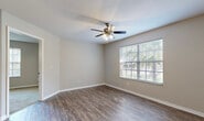 Located at Turtle Creek Blvd in Naples, Florida, this one-bedroom, one-bathroom unit offers a thoughtfully designed layout that maximizes its compact footprint. The open-concept living and kitchen area serves as the heart of the space, featuring durable wood-style plank flooring, neutral gray walls, and a ceiling fan with integrated lighting. A window allows natural light to filter in, offering views of lush Florida greenery.

The kitchen is well-equipped with rich, dark wood cabinetry, granite-look countertops, stainless steel appliances including a refrigerator, microwave, and range, and a peninsula that provides additional prep and seating space. Track lighting overhead enhances functionality. A louver-doored closet near the entrance provides convenient storage.

The bedroom is carpeted for comfort and features its own ceiling fan, a large window with natural light, and direct access to both a walk-in closet with built-in rod storage and the full bathroom. The bathroom is finished with dark wood vanity cabinetry, granite-style countertops, a large mirror, wood-style tile flooring, and a tub-shower combination, presenting a cohesive and refined aesthetic throughout the unit.