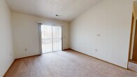Located at 906 Meadow Valley Dr in Northvue, PA, this one-bedroom, one-bathroom residence offers a practical and comfortable single-floor layout. The living area is thoughtfully divided into two connected spaces, both finished with soft wall-to-wall carpeting and a textured ceiling. A sliding glass door in the main living area floods the space with natural light and provides direct outdoor access, complemented by vertical blinds for privacy. A ceiling fan adds comfort to the secondary living zone, which flows seamlessly into the kitchen. The kitchen features warm wood-toned cabinetry, a peninsula with counter seating, a built-in range, refrigerator, and a single-basin sink — all supported by durable tile-style flooring. The bedroom is a well-proportioned retreat with plush carpeting, a window overlooking the exterior, and a sliding wood-panel closet door. An additional closet provides extra storage within the unit. The bathroom is clean and functional, equipped with a full tub and shower combo with chrome fixtures and tile-patterned flooring. A hallway connects the main areas of the home, completing this efficient and well-organized floor plan suited for comfortable everyday living.