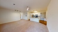 This single-floor residence at 2571 Seminole Trail in Charlottesville, Virginia offers a well-designed, open-concept layout that seamlessly connects the main living and kitchen areas. The living space features plush wall-to-wall carpeting, a ceiling fan, and track lighting, creating a comfortable and functional environment. Large windows dressed with blinds allow ample natural light to fill the room, enhancing its bright and airy ambiance.

The kitchen is a standout feature, outfitted with crisp white shaker-style cabinetry, granite countertops, and a suite of stainless steel appliances including a refrigerator, range, and microwave. A central island with an undermount sink and additional granite countertop space provides both prep area and casual seating. Pendant lighting and a subway tile backsplash add polished, modern touches, while hardwood-style flooring grounds the space with warmth.

The bathroom continues the refined aesthetic with granite countertops, white cabinetry, a large vanity mirror with overhead lighting, and a tub-shower combination. Hardwood-style flooring carries through into the bathroom as well.

The bedroom is generously sized, with carpeted flooring, a ceiling fan, and access to the bathroom. Throughout the residence, a consistent palette of white walls and neutral finishes contributes to a clean, cohesive feel.