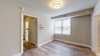 Located at 1303 Delaware Ave in Wilmington, Delaware, this single-floor unit offers a well-organized layout with a clean, updated aesthetic throughout. The living area features wood-look plank flooring, neutral-toned walls, and a window that allows natural light to filter into the space, creating a bright and welcoming atmosphere. A thermostat and HVAC vent are conveniently positioned, reflecting practical, functional design.

The kitchen is equipped with stainless steel appliances, including a gas range, dishwasher, and microwave, complemented by gray cabinetry, granite countertops, and a tile backsplash. Light ceramic tile flooring ties the kitchen together, providing a durable and easy-to-maintain surface.

The bathroom presents a classic design with white subway tile walls accented by a navy tile border, a soaking tub, and a black-and-white mosaic tile floor. A window above the tub brings in natural light, enhancing the bright, clean feel of the space.

A spacious walk-in closet with built-in shelving along multiple walls provides ample storage, while the entry area connects seamlessly to the kitchen and main living spaces. The unit's cohesive neutral palette and updated finishes contribute to a comfortable and functional living environment.