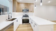 Located at 3510 NE 125th St in Seattle's Meadowbrook neighborhood, this contemporary three-floor home offers a thoughtfully designed layout across three well-proportioned levels. Light-toned hardwood flooring flows throughout the main living areas, complementing the clean white walls and recessed lighting that give the home a bright, modern feel.

The main level features an open-concept living and dining area that connects seamlessly to a stylish kitchen outfitted with warm wood cabinetry, white quartz countertops, a subway tile backsplash, stainless steel appliances including a gas range, and sleek black hardware. A kitchen island provides additional prep and gathering space, while pendant lighting adds a contemporary touch. Large windows invite natural light and outdoor views throughout.

The upper floors host three bedrooms, each with plush carpeting, generous windows, and good-sized closets. The dedicated office provides flexible space for work or study. Three bathrooms feature minimalist white vanities, quartz countertops, large-format tile flooring, and matte black fixtures and mirrors for a cohesive, modern aesthetic.

Additional conveniences include in-unit laundry, multiple staircases connecting the floors, and a wall-mounted mini-split system. The home's clean architectural lines and neutral palette create a calm, move-in-ready environment throughout.