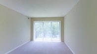 Located at 4695 Braddock Ct in Columbus, Ohio, this single-floor residence offers a clean, functional layout with a welcoming and comfortable ambiance. The living area is a standout feature of the space, highlighted by a full-width sliding glass door framed with vertical blinds that flood the room with abundant natural light. The expansive glass opening provides direct views of mature greenery outside, creating a seamless connection between the interior and the natural surroundings. Soft, neutral-toned carpeting runs throughout, complementing the warm beige walls and white trim for a cohesive, understated aesthetic. The smooth, well-maintained ceilings contribute to the open, airy feel of the space. A ceiling vent is positioned to ensure consistent climate control throughout the room. The overall design is straightforward and practical, offering a bright and pleasant environment with easy access to outdoor space. The abundance of natural light and the green views beyond the glass doors give the space a refreshing, tranquil character that makes it feel both open and inviting.