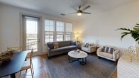 Located in Dallas's vibrant Deep Ellum neighborhood, this single-floor residence offers a thoughtfully designed open layout with contemporary finishes throughout. Warm hardwood flooring flows seamlessly from room to room, tying the space together with a cohesive, inviting aesthetic.

The galley-style kitchen is both functional and stylish, featuring white quartz countertops, a classic subway tile backsplash, a stainless steel appliance suite, and a combination of white upper cabinets and rich wood-toned lower cabinetry. A sliding barn door adds a modern industrial accent near the entryway.

The open living and dining area is bathed in natural light from large floor-to-ceiling windows fitted with roller shades, offering views to the outdoors. A ceiling fan enhances comfort in the spacious living room, which is well-proportioned for both relaxing and entertaining.

The bathroom continues the clean, modern palette with warm wood vanity cabinetry, white countertops, and hardwood-style flooring. An adjacent walk-in closet provides generous storage with built-in shelving and hanging space.

Throughout the residence, the design balances contemporary style with practical livability, creating a bright, well-appointed home in the heart of Dallas.