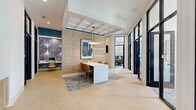 Located at 1153 Bees Ferry Rd in Johns Island, SC, this thoughtfully designed office space delivers a polished, contemporary work environment across a single floor. The open main area greets visitors with distinctive hexagonal tile flooring, coffered ceilings with teal accent trim, and warm wood panel wall detailing. A central communal work table anchors the space beneath a modern pendant light, while a built-in wood-and-white cabinetry unit provides functional storage accented by curated artwork.

Multiple private office rooms line the perimeter, each enclosed by floor-to-ceiling black steel-framed glass doors that flood the interiors with natural light while maintaining acoustic privacy. One standout private room features teal wainscoting panels, a round wood conference table with tan leather chairs, and a large window overlooking lush outdoor greenery. Additional workrooms offer dedicated desks, task seating, and decorative rugs, creating focused yet inviting individual workspaces.

A separate workstation area with bold, dramatic wallpaper adds visual contrast and character. Throughout the space, a cohesive palette of teal, warm wood tones, white, and black creates a refined yet welcoming atmosphere ideal for professional use. Generous natural light, high ceilings, and intentional design elements combine to make this a highly functional and aesthetically impressive office environment.