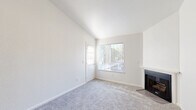 Located at 7434 Auburn Oaks Ct in Citrus Heights, California, this single-floor, 2-bedroom, 2-bathroom residence offers a well-organized layout with a bright, neutral palette throughout. The living room is a welcoming focal point, featuring vaulted ceilings, plush carpet, a wood-burning fireplace, and a large window with vertical blinds that allows natural light to fill the space. Adjacent to the living area is the combined kitchen and dining room, which offers two distinct configurations visible from the images — one featuring a peninsula-style counter with dark countertops, white cabinetry, stainless steel appliances including a range, microwave, and refrigerator, wood-look vinyl flooring, and a ceiling fan. A second kitchen view showcases a galley-style layout with matching white cabinetry and dual-basin stainless steel sink. Both bedrooms are carpeted and feature clean white walls; the primary bedroom includes vaulted ceilings, a window with natural views, and direct access to an en-suite bathroom. The second bedroom is generously sized with its own closet. Both bathrooms are finished with wood-look flooring and tub-shower combinations. Additional spaces include a hallway, laundry area, utility room, and two closets for ample storage.