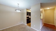 Located at 2515 Weatherby Dr in Arlington, Texas, this single-floor residence offers a practical and well-organized layout designed for comfortable everyday living. The open living and dining area is finished with plush wall-to-wall carpeting and features a ceiling fan with integrated lighting, built-in display shelves, and a sliding glass door that opens to a private balcony with outdoor views. A pendant light fixture anchors the dining space, which connects seamlessly to the kitchen through a pass-through opening. The kitchen is outfitted with dark cabinetry, granite-style countertops, black appliances including a microwave, range, and dishwasher, alongside a stainless steel refrigerator, all set atop warm hardwood-style flooring. The bedrooms are carpeted and bathed in natural light from large windows with blinds. The primary bedroom includes a spacious walk-in closet, while the secondary bedroom features a standard reach-in closet. Each room is equipped with ceiling fans for added comfort. The bathroom includes a full-size soaking tub and shower combination with clean white tile surround and chrome fixtures. Textured ceilings and neutral warm-toned walls are consistent throughout, giving the space a cohesive and inviting feel.
