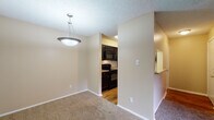 Located at 2515 Weatherby Dr in Arlington, Texas, this single-floor residence offers a practical and well-organized layout designed for comfortable everyday living. The open living and dining area is finished with plush wall-to-wall carpeting and features a ceiling fan with integrated lighting, built-in display shelves, and a sliding glass door that opens to a private balcony with outdoor views. A pendant light fixture anchors the dining space, which connects seamlessly to the kitchen through a pass-through opening. The kitchen is outfitted with dark cabinetry, granite-style countertops, black appliances including a microwave, range, and dishwasher, alongside a stainless steel refrigerator, all set atop warm hardwood-style flooring. The bedrooms are carpeted and bathed in natural light from large windows with blinds. The primary bedroom includes a spacious walk-in closet, while the secondary bedroom features a standard reach-in closet. Each room is equipped with ceiling fans for added comfort. The bathroom includes a full-size soaking tub and shower combination with clean white tile surround and chrome fixtures. Textured ceilings and neutral warm-toned walls are consistent throughout, giving the space a cohesive and inviting feel.