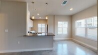 This single-story space showcases a contemporary design highlighted by polished concrete floors that extend throughout, lending a sleek, industrial character to every room. The open-concept layout seamlessly connects the kitchen and living area, creating a bright and cohesive environment bathed in natural light from multiple windows fitted with white shutters.

The kitchen is well-appointed with crisp white shaker-style cabinetry, dark countertops, and a full suite of stainless steel appliances, including a range, microwave, and dishwasher. A textured white tile backsplash adds visual interest, while a peninsula with a dark countertop and undermount sink anchors the space. Two mason jar-style pendant lights hang above, providing warm, focused illumination.

The bedrooms are comfortably sized, each featuring polished concrete floors, neutral-toned walls, ceiling fans, and windows that allow natural light to filter in. The bathroom is cleanly finished with a white vanity, stone-toned countertop, a large mirror, and a tub and shower combination with white tile surround and chrome fixtures. The overall ambiance is modern, clean, and functional throughout.