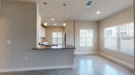 This single-story space showcases a contemporary design highlighted by polished concrete floors that extend throughout, lending a sleek, industrial character to every room. The open-concept layout seamlessly connects the kitchen and living area, creating a bright and cohesive environment bathed in natural light from multiple windows fitted with white shutters.

The kitchen is well-appointed with crisp white shaker-style cabinetry, dark countertops, and a full suite of stainless steel appliances, including a range, microwave, and dishwasher. A textured white tile backsplash adds visual interest, while a peninsula with a dark countertop and undermount sink anchors the space. Two mason jar-style pendant lights hang above, providing warm, focused illumination.

The bedrooms are comfortably sized, each featuring polished concrete floors, neutral-toned walls, ceiling fans, and windows that allow natural light to filter in. The bathroom is cleanly finished with a white vanity, stone-toned countertop, a large mirror, and a tub and shower combination with white tile surround and chrome fixtures. The overall ambiance is modern, clean, and functional throughout.