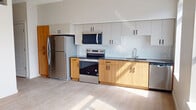 This 480 square foot apartment in Salt Lake City offers a thoughtfully designed living space. The kitchen is a standout feature, boasting a sleek design with a mix of white upper cabinets and warm wood lower cabinets. It's equipped with stainless steel appliances, including a full-size refrigerator, oven with cooktop, and built-in microwave. The countertops are a stylish dark gray, complementing the white subway tile backsplash.

The living area is open and bright, with light-colored walls and wood-look flooring that extends throughout the apartment. Large windows allow natural light to flood the space, creating an airy atmosphere. The bedroom, measuring 100 square feet, features plush carpeting and a sliding closet door for efficient storage.

The bathroom continues the modern aesthetic with a white vanity, undermount sink, and a shower/tub combination. The apartment's layout maximizes the available space, with clever storage solutions evident in the closets and kitchen design. Despite its compact size, this apartment offers a comfortable and contemporary living environment in the heart of Salt Lake City.
