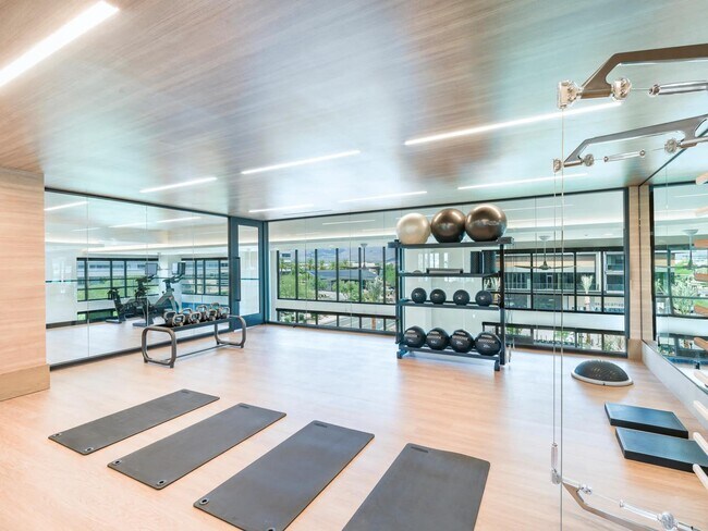 Estírese, levante o fluya en el estudio de fitness lleno de luz, que cuenta con colchonetas de yoga, pesas y espejos desde el piso hasta el techo. - Modera Reserve
