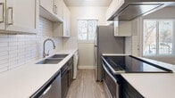 Located at 768 S 900 E in Salt Lake City, Utah, this one-bedroom, one-bathroom unit offers a thoughtfully organized layout across a single floor. The open-concept living and kitchen area serves as the heart of the space, featuring warm luxury vinyl plank flooring and a ceiling fan with integrated lighting. A kitchen peninsula with a white quartz countertop separates the two areas, providing additional prep and dining space. The galley-style kitchen is well-appointed with white upper cabinetry, dark lower cabinets, a classic white subway tile backsplash, stainless steel appliances including a refrigerator, dishwasher, and range with a wall-mounted hood vent, plus a double-basin sink and in-unit washer. A window above the sink allows natural light to brighten the space. The bedroom features plush carpet flooring, a natural light source via a window with blinds, and impressive storage capacity courtesy of two sets of double bi-fold closet doors. The bathroom is finished with floor-to-ceiling white subway tile surrounding a soaking tub and shower combo, complemented by brushed nickel fixtures and wood-look tile flooring. Neutral gray walls and clean white trim throughout lend the entire unit a modern, cohesive aesthetic.