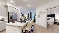 This thoughtfully designed 1-bedroom, 1-bathroom residence offers a seamless open-concept layout finished with light wood-style flooring and crisp white walls throughout. The modern kitchen is a standout feature, showcasing gray flat-front cabinetry, quartz countertops, stainless steel appliances including a French door refrigerator, and a generous island with bar seating — ideal for both everyday meals and entertaining. The kitchen flows effortlessly into the living room, which is bathed in natural light from large windows dressed with stylish striped drapes and offers access to an outdoor area. Recessed lighting and a ceiling fan add comfort and functionality to the living space. The spacious bedroom provides a tranquil retreat, featuring soft neutral tones, ample natural light, and direct sightlines to the kitchen area. A dedicated closet offers convenient storage. The bathroom is finished with clean white subway tile in a walk-in shower enclosed by a glass panel door, lending a sleek, spa-like quality. Throughout the residence, consistent use of light flooring, modern fixtures, and a neutral palette creates a cohesive, contemporary ambiance that is both inviting and functional.