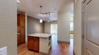 Located at 16035 E Easter Cir in Aurora, CO, this single-story 1-bedroom, 1-bathroom residence offers a thoughtfully designed layout that maximizes its compact footprint. The open-concept kitchen and living area serves as the heart of the home, anchored by a central kitchen island with granite countertops and built-in shelving. The kitchen is well-equipped with rich warm-toned wood cabinetry, granite countertops, stainless steel appliances including a refrigerator and dishwasher, and a ceiling-mounted track lighting system. Hardwood-style flooring flows throughout the main living areas, complemented by neutral-toned walls that lend a bright, airy feel. The living room features a ceiling fan and a sliding glass door with vertical blinds, allowing natural light to fill the space. The bedroom is carpeted for comfort, includes its own ceiling fan, a window with outdoor views, and access to a dedicated closet. The bathroom is finished with wood-toned cabinetry, a tiled shower-tub combination with chrome fixtures, and hardwood-style flooring. A hallway connects the private areas of the residence seamlessly. Overall, the space offers a clean, functional, and comfortable living environment.