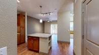 Located at 16035 E Easter Cir in Aurora, CO, this single-story 1-bedroom, 1-bathroom residence offers a thoughtfully designed layout that maximizes its compact footprint. The open-concept kitchen and living area serves as the heart of the home, anchored by a central kitchen island with granite countertops and built-in shelving. The kitchen is well-equipped with rich warm-toned wood cabinetry, granite countertops, stainless steel appliances including a refrigerator and dishwasher, and a ceiling-mounted track lighting system. Hardwood-style flooring flows throughout the main living areas, complemented by neutral-toned walls that lend a bright, airy feel. The living room features a ceiling fan and a sliding glass door with vertical blinds, allowing natural light to fill the space. The bedroom is carpeted for comfort, includes its own ceiling fan, a window with outdoor views, and access to a dedicated closet. The bathroom is finished with wood-toned cabinetry, a tiled shower-tub combination with chrome fixtures, and hardwood-style flooring. A hallway connects the private areas of the residence seamlessly. Overall, the space offers a clean, functional, and comfortable living environment.