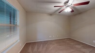 Located at 8805 North Plaza in Austin, Texas, this single-floor unit offers a practical and comfortable layout designed for everyday living. The living area greets you at the entry, featuring warm neutral-toned carpet, a large window with blinds that allows natural light to filter through while offering views of surrounding greenery, and a clean white front door. The galley-style kitchen is efficiently arranged with ample white cabinetry above and below the countertops, a double-basin stainless steel sink, and a full suite of white appliances including a coil-top electric range with oven and a refrigerator. Wood-look flooring runs throughout the kitchen, adding warmth and easy maintenance. The bedrooms are carpeted and finished in soft beige tones, each equipped with a ceiling fan with light fixture and textured ceilings. One bedroom features a window overlooking lush outdoor foliage, providing natural light and a pleasant view. The bathroom is accessible via a hardwood-floored hallway and includes a tiled shower-tub combination, a vanity, and a toilet. Adjacent to the bathroom, a dedicated closet provides convenient storage. The unit's neutral color palette and functional design create a cohesive and livable atmosphere throughout.