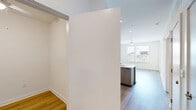 Located at 900 N Allen Ave in Richmond, VA, this thoughtfully designed 2-bedroom, 2-bathroom unit offers a clean, modern aesthetic throughout its efficiently arranged single-floor layout. Light wood-tone flooring flows consistently through the living spaces, complementing the bright white walls that give the home an airy, open feel.

The combined kitchen and living area serves as the heart of the unit. The kitchen features a central island with a white quartz countertop and an integrated sink, white flat-front cabinetry extending to the ceiling, and a full suite of stainless steel appliances including a French door refrigerator, electric range, and built-in microwave. Recessed lighting illuminates the space effectively.

The primary bedroom is a comfortable size and includes a walk-in closet with built-in shelving and a ceiling fan with a window that brings in natural light. It is also served by a stylish barn-style sliding door that leads to a dedicated bathroom area with an in-unit stacked washer and dryer. The second bedroom benefits from dual windows overlooking the outdoors, flooding the room with natural light. Both bathrooms are finished with neutral tile flooring, vanities with understated hardware, and a tub-shower combination. A glass-paneled exterior door in the living area provides additional natural light and outdoor access.