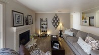 This single-floor residence offers a thoughtfully arranged layout that balances comfort and functionality across its key living spaces. The living room serves as a central gathering area, highlighted by a classic fireplace with a white paneled surround and framed botanical artwork displayed on the mantel. Crown molding adds a refined architectural detail, while a sliding glass door invites natural light and provides direct access to an outdoor patio. Neutral-toned carpet, decorative wall accents, and warm ambient lighting contribute to an inviting atmosphere.

Adjacent to the living room, the dining area features hardwood-style flooring and crown molding, centered around a pendant light fixture that illuminates the space. A passthrough connects seamlessly to the kitchen, which is equipped with warm oak cabinetry, granite-style countertops, and hardwood-style flooring, providing a practical and efficient workspace.

The two bedrooms are carpeted and comfortably sized, each featuring windows that allow natural light to fill the rooms. The primary bedroom includes a walk-in closet, while both rooms offer a calm, restful ambiance with neutral wall tones.

The bathroom provides a full-sized soaking tub with shower combination, a dual-sink vanity with oak cabinetry, and tile flooring, delivering both practicality and ease of use.