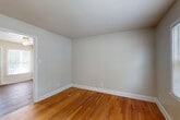 Located at 5402 Friendly Manor Dr in Greensboro, NC, this two-story, two-bedroom, two-bathroom home offers a practical and comfortable layout spread across two floors of nearly equal size. Warm hardwood flooring flows throughout the main living areas and bedrooms, lending a consistent and inviting character to the space.

The main floor houses the living room and kitchen. The living room is bright and airy, featuring large windows with blinds that allow natural light to filter in alongside views of the surrounding greenery. A baseboard heating unit runs beneath the windows. The kitchen is well-equipped with warm oak cabinetry, white appliances including a refrigerator, range, and microwave, light countertops, and durable wood-look flooring. A peninsula counter provides additional workspace and a natural separation between the kitchen and entry area.

Both bedrooms feature the same warm hardwood floors and neutral wall tones, with the primary bedroom offering a generous footprint. Bedrooms are served by closets with sliding doors and built-in rods for convenient storage. A total of three closets are distributed throughout the home.

The two bathrooms are clean and functional. One features a tub-shower combination with white tile surround, while both include wood-toned vanities with white countertops and mirror-and-light fixtures above. Dark hardwood flooring completes the bathroom spaces. Two staircases connect the floors, providing efficient circulation throughout the home.