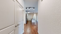 This single-floor, 3-bedroom, 2-bathroom home offers a thoughtfully designed open-concept layout that balances comfort and functionality. Rich wood-look flooring flows throughout the main living areas, while the entryway hall, lit by a modern track lighting fixture, leads seamlessly into the heart of the home.

The kitchen is a standout feature, boasting dark wood cabinetry that extends to the ceiling, a mosaic tile backsplash, stainless steel appliances including a full-size refrigerator, electric range, and built-in microwave, and a large center island with a granite countertop and double sink. Warm pendant lighting above the island adds an inviting ambiance. The kitchen opens directly to the dining and living areas, creating an ideal space for entertaining.

The living room is bright and airy, featuring a ceiling fan, smooth white walls, and sliding glass doors that open to a private balcony with exterior views. Two additional bedrooms feature plush carpeting, ceiling fans, and natural light from window blinds.

Both bathrooms are finished with neutral tile flooring, wood-toned tile surrounds, and granite-topped vanities. The primary bathroom includes a soaking tub alongside a separate walk-in shower with decorative mosaic tile accents. Throughout the home, clean white panel doors and crisp white walls contribute to a modern, move-in-ready aesthetic.