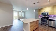 This 680 square foot apartment at Peridot Palms offers a harmonious blend of modern design and functionality. The heart of the home is a sleek, open-concept kitchen featuring light wood-grain cabinetry, stainless steel appliances, and a striking purple mosaic tile backsplash. The kitchen island doubles as a dining area, seamlessly transitioning into the living space.

The spacious 150 square foot bedroom boasts a large window with white blinds, providing ample natural light and a view of the surrounding greenery. A ceiling fan ensures comfort, while the neutral walls and wood-look flooring create a serene atmosphere.

Two well-appointed bathrooms feature contemporary vanities with quartz countertops, large mirrors, and stylish fixtures. The main bathroom includes a shower/tub combination, while the second offers additional convenience.

Throughout the apartment, wood-look vinyl flooring adds warmth and durability. The living area is bright and airy, with windows that flood the space with natural light. Track lighting and recessed fixtures provide additional illumination options.

A convenient in-unit laundry area and closet space offer practical storage solutions. The cohesive design aesthetic, with its neutral color palette and modern touches, creates a sophisticated and inviting living environment in this compact yet well-designed apartment.
