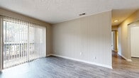 Located at 10612 SR-204 E in Savannah, Georgia, this single-floor unit offers a practical and comfortable layout designed for everyday living. The living area features durable wood-look hard flooring paired with vertical panel wall accents and a sliding glass door fitted with vertical blinds, allowing natural light to flow in and providing access to the outdoors. Textured ceilings are found throughout the unit, lending a consistent finish across all rooms.

The kitchen is efficiently designed with a classic L-shaped layout, featuring dark espresso-toned cabinetry with brushed hardware, light granite-look countertops, and a full suite of black appliances including a refrigerator, range, dishwasher, and microwave. The wood-look flooring continues here, complementing the kitchen's functional aesthetic.

The bedrooms are carpeted for comfort and include windows dressed with horizontal blinds, providing natural light and outdoor views. Closet space is available, and the neutral wall tones create a clean, move-in-ready feel throughout.

The bathroom includes a full-size soaking tub with an integrated surround, chrome fixtures, and hard flooring, maintaining the unit's consistent and practical design language. Overall, the space presents a well-maintained, neutral palette that is both functional and inviting.