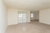 Located at 4103 Wesley Club Dr in Decatur, GA, this single-floor unit offers a practical and straightforward layout designed for comfortable everyday living. The open living area is generously sized, finished with neutral-toned carpet and light-colored walls that create a clean, bright atmosphere. A large sliding glass door with vertical blinds allows natural light to fill the space and provides an outdoor connection. An adjoining carpeted area extends the living space, offering flexibility for various uses. The kitchen is well-equipped, featuring warm oak cabinetry, white countertops, a white electric range, a dishwasher, and a sink — all set atop durable hardwood-style flooring. Multiple bedrooms are finished with plush carpet, textured ceilings, and windows that bring in natural light with views of the surrounding neighborhood. The bathroom includes a tiled tub and shower combination, a toilet, a vanity, and hardwood-style flooring, offering a clean and functional design. Throughout the unit, neutral tones and consistent finishes contribute to a cohesive and inviting atmosphere, making this a well-rounded space in a convenient Decatur location.