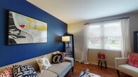 Located at 1361 Presidential Drive in Columbus, Ohio, this single-floor residence offers a thoughtfully designed layout that balances comfort and style. The living room serves as the focal point of the home, anchored by a striking deep-blue accent wall that adds a bold, modern touch. Warm hardwood-style flooring runs throughout the main living areas, complemented by natural light streaming through windows dressed with blinds and sheer curtains. Built-in shelving along the walls provides both function and character.

The dining area sits adjacent to the entry, featuring a ceiling fan and wall-mounted decorative accents, creating an inviting space for everyday meals. The kitchen is well-equipped with warm wood cabinetry, dark granite-style countertops, a gas range, and a sink workspace, all laid over matching hardwood-style flooring that ties the space together cohesively.

The bedroom makes a statement with a vibrant terracotta-red accent wall and a window that brings in natural light. It features plush carpeting, a spacious closet with built-in shelving, and the added convenience of an in-unit stacked washer and dryer.

The bathroom is clean and functional, offering a full soaking tub with white tile surround and a shower curtain enclosure alongside a white vanity. Overall, the residence presents a welcoming and characterful living environment.