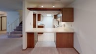 This two-floor residence offers a well-organized layout with a variety of functional living spaces throughout. The kitchen features warm wood-toned cabinetry, recessed lighting, a skylight, a built-in breakfast bar with ample counter space, and standard appliances including a range and refrigerator. It opens toward the main living area, creating an accessible and connected feel.

The living areas are generously proportioned, finished with plush carpeting and neutral-toned walls that lend a clean, understated aesthetic. A large sliding glass door in one of the main rooms allows natural light to filter in and provides access to an outdoor area. A ceiling fan adds comfort to the space.

The bedrooms are well-sized with soft carpeting, standard windows offering natural light, and warm wood baseboards and door trim throughout. Each bedroom is complemented by a walk-in closet outfitted with multi-tiered wire shelving systems, offering substantial and well-organized storage capacity.

Both bathrooms are finished with classic white tile flooring in a small-grid mosaic pattern. One bathroom includes a full tub-and-shower combination, while both feature wood-fronted vanities with integrated sinks and large mirrors. The lower level includes an expansive open area with pendant lighting, suitable for use as a recreation or bonus room. Textured ceilings are consistent throughout the home.