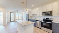 Located at 8353 Auterra Drive in Melbourne, Florida, this well-designed one-bedroom, one-bathroom residence offers a thoughtfully organized single-floor layout. The open-concept living, dining, and kitchen area serves as the heart of the home, finished with light wood-tone flooring that enhances the bright, airy atmosphere. The kitchen is a standout feature, showcasing a two-tone cabinet design with crisp white uppers and slate-blue lowers, granite countertops, a central island with pendant lighting, and a full suite of stainless steel appliances including a refrigerator with ice dispenser, range, microwave, and dishwasher. Natural light flows in through large windows, complemented by recessed lighting and a ceiling fan in the living area. The bedroom is a comfortable retreat carpeted for warmth, with dual windows offering pleasant outdoor views and access to two generous closets, including a walk-in with built-in wire shelving. The bathroom is sleek and modern, featuring a double-sink granite vanity, light wood-tone flooring, and a glass-enclosed walk-in shower. Additional conveniences include an in-unit laundry area and a private balcony, rounding out this efficiently designed Florida residence.