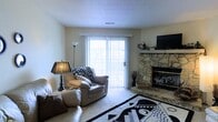 This residence at Bryce De Moray Apartments offers a thoughtfully designed single-floor layout that combines comfort and functionality. The living room serves as the heart of the space, drawing immediate attention with its striking floor-to-ceiling stone fireplace — a standout architectural feature that adds warmth and rustic character to the room. A large sliding glass door floods the area with natural light, offering a bright, welcoming atmosphere and easy access to the outdoors. The living room is finished with plush wall-to-wall carpeting, contributing to a cozy and inviting ambiance. A textured ceiling adds a subtle design element consistent throughout the space. The neutral wall tones create a versatile backdrop, making the space easy to personalize. The overall layout is efficient and comfortable, ideal for everyday living. With its combination of natural light, a distinctive stone fireplace, and practical design, this unit at Bryce De Moray Apartments presents a well-rounded living environment suited to a variety of lifestyles.