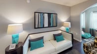 Located at 3115 Grand Ave in Pinellas Park, Florida, this thoughtfully designed single-floor residence offers a seamless blend of modern aesthetics and functional living. A consistent teal and gray color palette ties each room together, creating a cohesive and inviting atmosphere throughout.

The open-concept kitchen is a standout feature, showcasing rich dark cabinetry, stainless steel appliances, granite countertops, and a large central island with bar seating and pendant lighting overhead. Dark hardwood-style flooring extends throughout the main living areas, complementing the kitchen's bold design. The adjacent dining and living areas provide ample room for both entertaining and everyday comfort, with the living room anchored by a stylish sofa and framed wall art.

The bedrooms are well-appointed, each benefiting from natural light through windows dressed with teal accent curtains and white blinds. Dark hardwood-style flooring continues into each bedroom, adding warmth and continuity. A flexible bonus room with open shelving and a floor lamp serves well as a home office or study.

The bathrooms feature granite-topped vanities with dark cabinetry, large-format tile flooring, and glass-enclosed shower options, reflecting the same refined design standards found throughout the home. Every detail of this residence reflects a deliberate, modern sensibility balanced with comfortable, livable spaces.