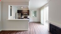 Located in the desirable Westwood neighborhood of Los Angeles, this single-floor residence at 11983 Wellworth Ave offers a well-designed, open-concept layout with modern finishes throughout. Rich hardwood-style flooring runs continuously across the living spaces, adding warmth and cohesion to the interior.

The living area is bright and spacious, anchored by a classic fireplace and floor-to-ceiling vertical blinds that frame sliding glass doors, allowing generous natural light to fill the room. Crown molding adds an elegant architectural detail to the main living space.

The kitchen is thoughtfully designed with dark espresso cabinetry, light quartz countertops, and a full suite of stainless steel appliances, including a gas range, microwave, and refrigerator. A peninsula with bar-height seating opens the kitchen to the living area, making it ideal for both cooking and entertaining. A bold red pendant light adds a distinctive design accent above.

The bedrooms are well-proportioned and bright, each featuring large windows with vertical blinds that provide views of surrounding greenery and ample natural light. Recessed lighting keeps the rooms feeling clean and modern.

Two full bathrooms are finished in neutral tones, each equipped with a shower-tub combination, vanity with storage, and chrome fixtures, offering functional and comfortable everyday spaces.