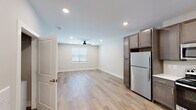 Located on Halsey Ave NE in Huntsville, Alabama, this single-floor unit offers a clean, modern interior designed for comfortable everyday living. The open-concept main area seamlessly connects the living space and kitchen, finished with light wood-style flooring that extends throughout the common areas. Recessed lighting and a ceiling fan keep the space well-lit and well-ventilated, while a window with blinds allows natural light to filter in.

The kitchen is thoughtfully appointed with rich, dark taupe cabinetry featuring brushed nickel hardware, light-toned countertops, and a full suite of stainless steel appliances including a refrigerator, electric range, microwave, and dishwasher. Ample upper and lower cabinet storage adds practicality to the space.

The bedroom features plush carpeting, a ceiling fan with light fixture, and a window overlooking the exterior, creating a comfortable and restful environment. The full bathroom is finished with wood-look tile flooring, a single vanity with a framed mirror and stylish exposed-bulb lighting, and a shower/tub combination. Neutral gray tones and clean white fixtures give the bathroom a crisp, contemporary feel.

The entry area provides a welcoming transition into the unit, complete with a paneled white door and additional closet storage. Overall, the space presents a cohesive, updated aesthetic suitable for modern living.