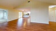 Located at 5945 Vinecroft Dr in Clarence Center, NY, this well-appointed single-floor home offers 2 bedrooms, 2 bathrooms, a den, and an attached garage. The open-concept kitchen and living area is a standout feature, highlighted by soaring vaulted ceilings, warm hardwood flooring, and a striking arched window that floods the space with natural light. The kitchen is thoughtfully designed with white cabinetry, granite countertops, stainless steel appliances, a center island, and vibrant yellow accent walls, complemented by decorative pendant lighting. A sliding glass door provides convenient outdoor access. The spacious primary bedroom is carpeted and features dual closets and generous windows, while the second bedroom also offers plush carpeting, natural light, and ample closet space. Both bathrooms are clean and functional, each featuring walk-in shower stalls and tile flooring — one finished in soft blue tones and the other in light lavender. The den provides additional flexible living space, and the hallway connects the home's layout efficiently. The attached garage includes direct interior access and a utility sink, adding everyday convenience to this comfortable Clarence Center residence.