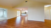 Located at 5945 Vinecroft Dr in Clarence Center, NY, this well-appointed single-floor home offers 2 bedrooms, 2 bathrooms, a den, and an attached garage. The open-concept kitchen and living area is a standout feature, highlighted by soaring vaulted ceilings, warm hardwood flooring, and a striking arched window that floods the space with natural light. The kitchen is thoughtfully designed with white cabinetry, granite countertops, stainless steel appliances, a center island, and vibrant yellow accent walls, complemented by decorative pendant lighting. A sliding glass door provides convenient outdoor access. The spacious primary bedroom is carpeted and features dual closets and generous windows, while the second bedroom also offers plush carpeting, natural light, and ample closet space. Both bathrooms are clean and functional, each featuring walk-in shower stalls and tile flooring — one finished in soft blue tones and the other in light lavender. The den provides additional flexible living space, and the hallway connects the home's layout efficiently. The attached garage includes direct interior access and a utility sink, adding everyday convenience to this comfortable Clarence Center residence.