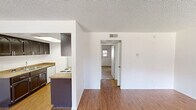 Located at 10134 W Mohawk Ln in Peoria, Arizona, this single-story, one-bedroom, two-bathroom home offers a practical and comfortable layout. The open living room greets you at the entrance, featuring wood-look laminate flooring, bright white walls, and large windows fitted with blinds that invite natural light and views of the surrounding greenery. A textured ceiling adds character throughout the main living areas. The galley-style kitchen is a functional highlight, showcasing dark espresso cabinetry, granite-style countertops, a double basin sink, a skylight overhead, and white appliances including a range and refrigerator — all set atop matching wood-look flooring. The generously sized primary bedroom is carpeted for comfort and includes a ceiling fan, a textured ceiling, and direct access to a well-appointed en-suite bathroom featuring dark vanity cabinetry and granite-style counters. A second full bathroom serves the rest of the home, complete with a shower/tub combo equipped with grab bars, a large mirror, and matching granite-style countertops. A connecting hallway ties the layout together efficiently, making this home a well-organized and inviting space in the heart of Peoria, AZ.