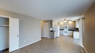 This single-floor residence offers two bedrooms and two bathrooms within an open, flowing layout. The living area is spacious and bright, featuring light-toned luxury vinyl plank flooring that extends throughout the main living space, providing a clean and cohesive aesthetic. Neutral gray walls complement the modern finishes and create a versatile backdrop for any décor style.

The kitchen is open to the living area and is well-appointed with light wood-toned cabinetry offering generous storage space. Dark countertops provide a subtle contrast against the cabinetry, while white appliances — including a refrigerator, range, microwave, and dishwasher — keep the space looking clean and functional. A peninsula-style island adds additional prep and storage space, further enhancing the kitchen's practicality.

A ceiling fan is centrally positioned in the kitchen area, promoting air circulation throughout the open-concept space. A louvered closet door near the entry adds a classic touch and provides convenient storage. The overall ambiance is modern, clean, and move-in ready, making it a practical and comfortable living space.