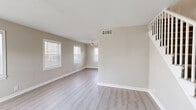This two-story, 2-bedroom, 1-bathroom home is thoughtfully laid out across two evenly sized floors, offering a comfortable and functional living environment. The main level features a combined dining and living area finished with light wood-style laminate flooring and neutral warm-toned walls. Multiple windows dressed with white blinds allow generous natural light to fill the space, while a ceiling fan adds practicality. The open layout flows naturally between the living area and the kitchen, which is connected via a pass-through window and features white shaker cabinetry, light stone-look countertops, a dishwasher, a refrigerator, and direct exterior access through a back door. The bathroom includes a full tub-shower combo with classic white tile surround and a window for natural ventilation. Upstairs, both bedrooms are carpeted in neutral tones and equipped with ceiling fans and ample natural light from multiple windows. The primary bedroom is generously sized and includes a dedicated closet. A second bedroom with its own closet and window completes the upper level. Throughout the home, a consistent neutral color palette, clean white trim, and multiple closets provide a clean, organized, and move-in ready feel.