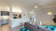 This single-floor residence offers a thoughtfully designed open-concept layout that seamlessly connects the main living areas. The living room is a comfortable, well-lit space featuring crown molding, wood-look flooring, a ceiling fan with light kit, and a sliding glass door that invites natural light and outdoor views. The adjacent dining area is defined by its own window with horizontal blinds and crown molding details, creating an intimate setting for meals.

The galley-style kitchen is efficiently organized, featuring gray shaker-style cabinetry, white countertops, stainless steel appliances including a refrigerator, microwave, and electric range, along with a built-in desk nook that provides a functional workspace. A peninsula counter connects the kitchen to the living area, enhancing the open flow of the space.

Both bedrooms are carpeted and include ceiling fans and large windows that allow ample natural light. The primary bedroom features an en-suite bathroom with gray cabinetry, a white countertop vanity, a large mirror, wood-look flooring, and a shower with curtain enclosure. The overall color palette throughout is neutral and cohesive, complemented by consistent trim and molding details.