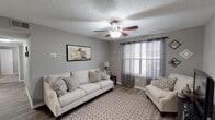 This single-floor residence offers a thoughtfully designed layout that balances comfort and functionality throughout. The living room serves as the heart of the home, featuring warm wood-look flooring, neutral gray walls, a textured ceiling with a ceiling fan, and a window dressed with sheer curtains that invite natural light. Plush seating and a patterned area rug create a welcoming atmosphere.

The kitchen is a standout space, outfitted with crisp white shaker-style cabinetry, light marble-look countertops, a blue subway tile backsplash, and stainless steel appliances including a refrigerator, range, and dishwasher. Light wood-look flooring ties the space together seamlessly. An adjacent dining area provides a defined space for meals, complete with wood flooring, chair-rail molding, and overhead lighting.

Both bedrooms are carpeted and feature ceiling fans, neutral toned walls, and windows with natural light. Each bathroom includes a tub-shower combination with clean white tile surround and wood-look flooring. A dedicated laundry closet with wire shelving accommodates a full-size washer, adding everyday convenience. Throughout, the consistent gray palette and cohesive finishes lend the space a clean, modern character.