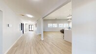 Located at 11 N 28th St in Las Vegas, NV, this single-floor clubhouse offers a clean, contemporary design across a generous and well-organized layout. Light wood-look flooring flows consistently throughout the space, complementing the neutral gray and white walls that lend a bright, professional atmosphere.

The expansive living room serves as the centerpiece of the clubhouse, featuring soaring ceilings, a row of large windows that invite abundant natural light, and a striking black-and-white patterned accent wall. Comfortable brown leather seating arranged around a modern white coffee table creates an inviting lounge area, while a built-in counter with dark cabinetry provides a convenient refreshment station.

A built-in workstation area with sleek pendant lighting and bar-height seating offers a collaborative workspace, while a private office is equipped with a full desk setup, dual monitors, ample cabinetry, and windows overlooking the surroundings. A second office space provides additional workspace with natural light and room for a printer station.

The hallway connects all areas efficiently, leading from the glass-paned front entry doors to each room. A compact, functional bathroom with a wall-mounted sink, mirror, and clean fixtures completes the layout. Together, these spaces make this clubhouse a practical and polished facility.