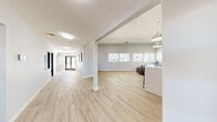 Located at 11 N 28th St in Las Vegas, NV, this single-floor clubhouse offers a clean, contemporary design across a generous and well-organized layout. Light wood-look flooring flows consistently throughout the space, complementing the neutral gray and white walls that lend a bright, professional atmosphere.

The expansive living room serves as the centerpiece of the clubhouse, featuring soaring ceilings, a row of large windows that invite abundant natural light, and a striking black-and-white patterned accent wall. Comfortable brown leather seating arranged around a modern white coffee table creates an inviting lounge area, while a built-in counter with dark cabinetry provides a convenient refreshment station.

A built-in workstation area with sleek pendant lighting and bar-height seating offers a collaborative workspace, while a private office is equipped with a full desk setup, dual monitors, ample cabinetry, and windows overlooking the surroundings. A second office space provides additional workspace with natural light and room for a printer station.

The hallway connects all areas efficiently, leading from the glass-paned front entry doors to each room. A compact, functional bathroom with a wall-mounted sink, mirror, and clean fixtures completes the layout. Together, these spaces make this clubhouse a practical and polished facility.